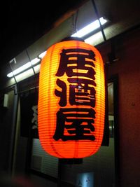 Lámpara anunciando un izakaya en la puerta de un local
